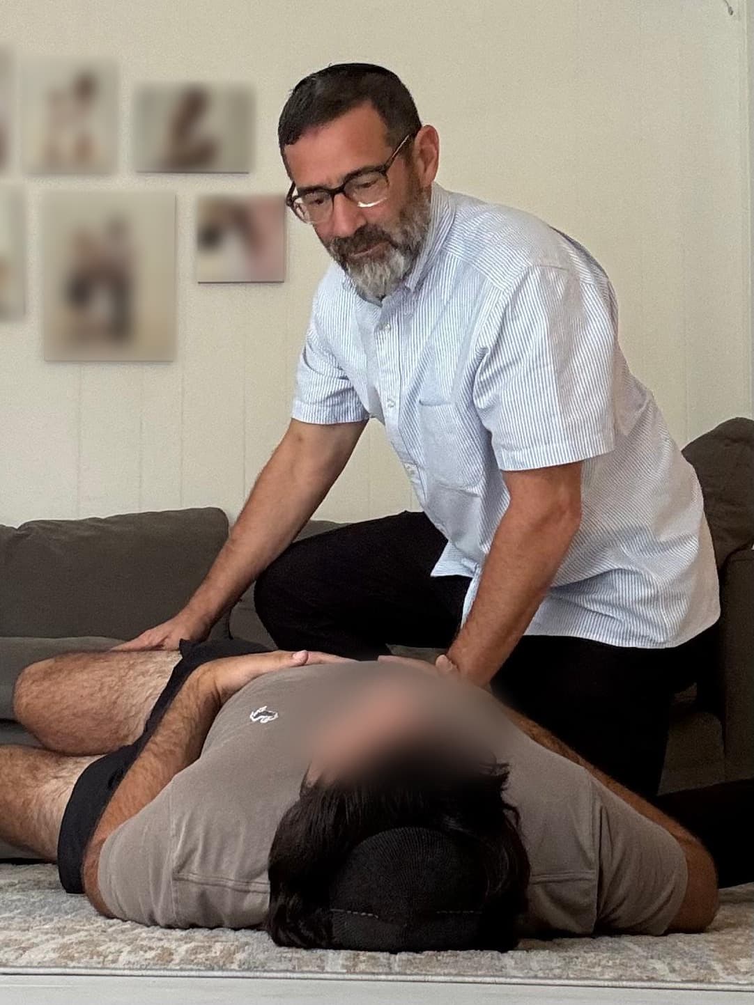 Chaim Backman working with both hands on a client's lower back during a session in their living room