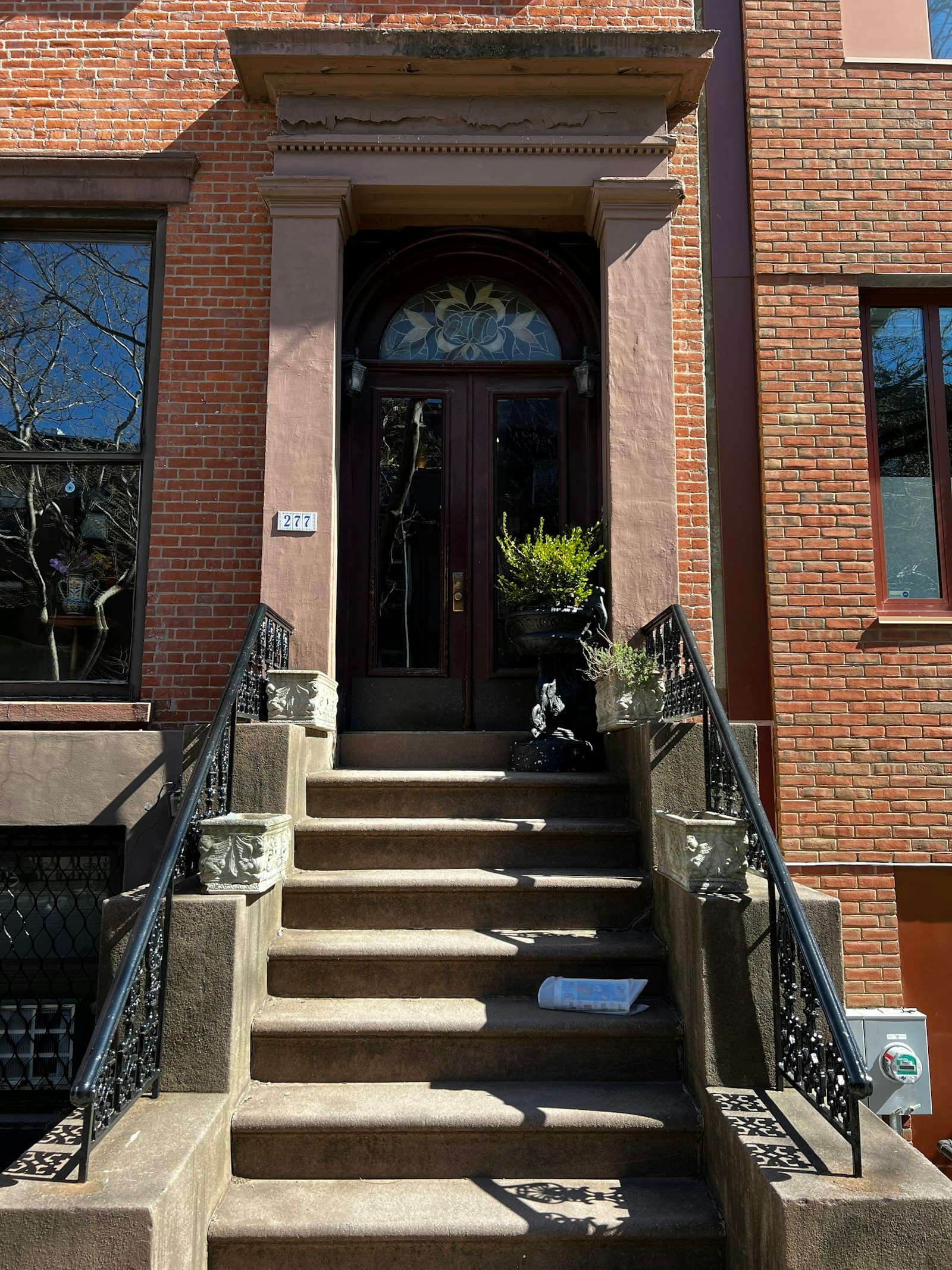 A brownstone stoop climbing past iron railings to a front door