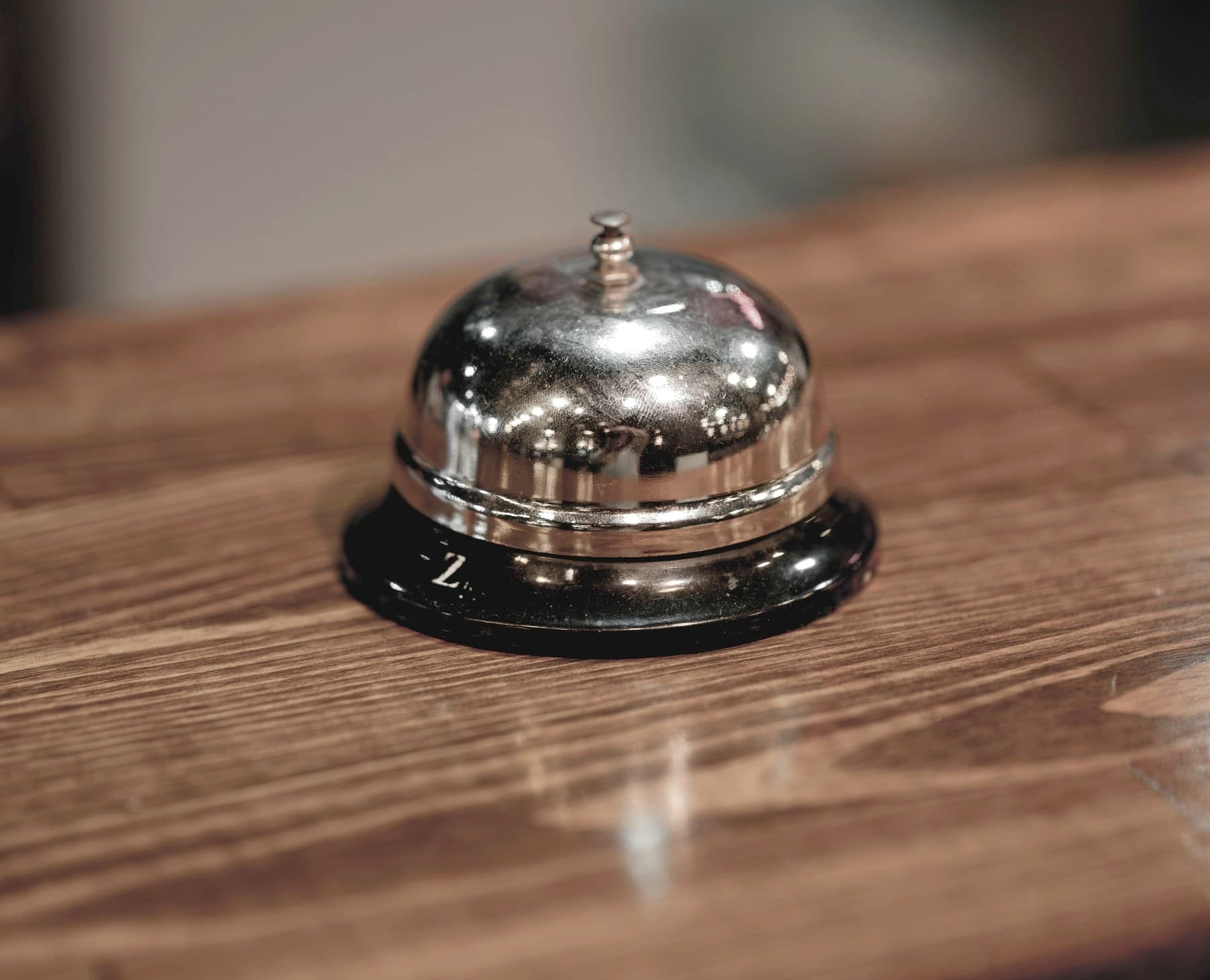 A polished reception bell on a wooden counter, lit warmly from one side