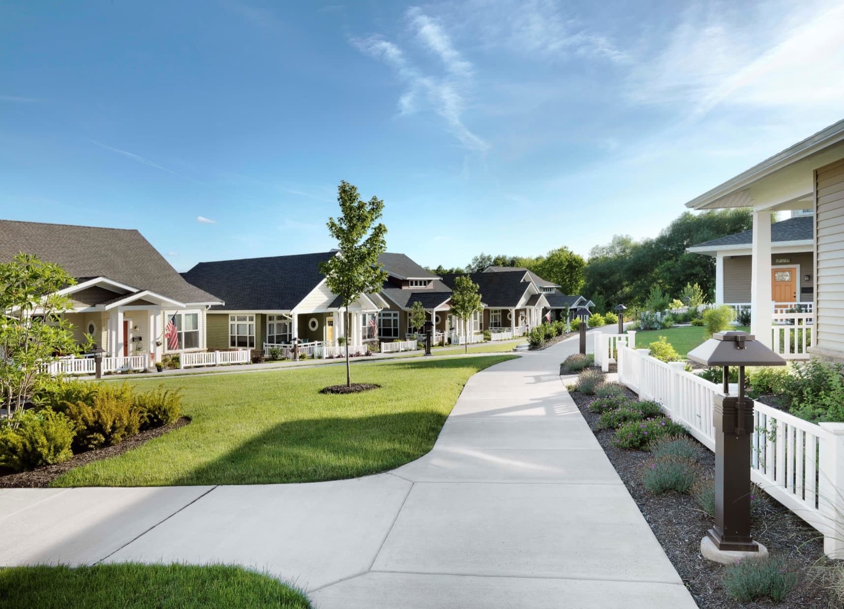 A row of single-story cottages along a landscaped walkway in a senior living community